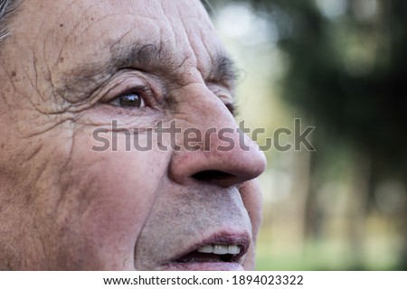Eyes of a senior man, outdoors, nature. Looking away, thoughtful, thinking. Close up of senior man face and eye