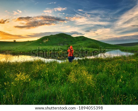 woman on the banks of the picturesque river. tourist is enjoying the morning landscape. colorful spring sunrise