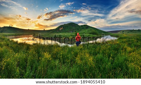 woman on the banks of the picturesque river. tourist is enjoying the morning landscape. colorful spring sunrise