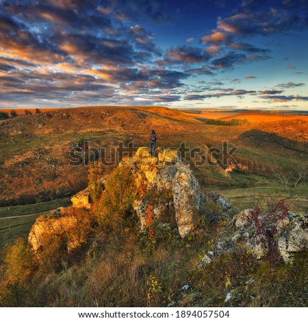 Woman on a hiking trip in the mountains walking on rocks. colorful autumn sunrise