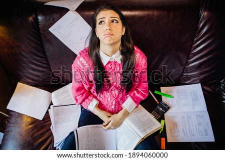 Worried female student stressing about exams and school. Studying at home, online class learning difficulties.College exam frustration. School-related anxiety. Notes and test books Royalty-Free Stock Photo #1894060000