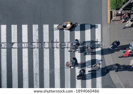 top aerial view of blur men and women in winter cloth and business dress walk and ride bicycle across crosswalk in street. Concept normal life of massive people with transportation.