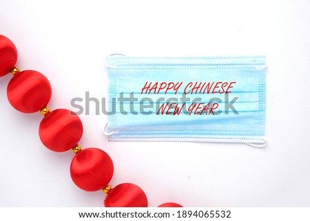 A picture of face mask written Happy Chinese New Year and red ball for decoration. This year will celebrate with pandemic situation.
