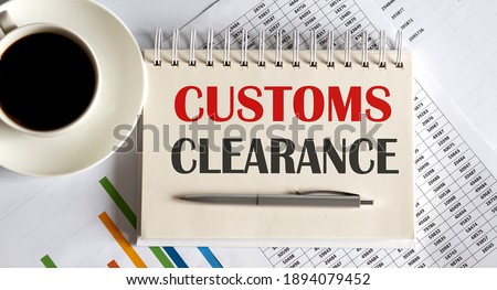 Notepad with text Customs Clearance, on the business charts and pen and coffee