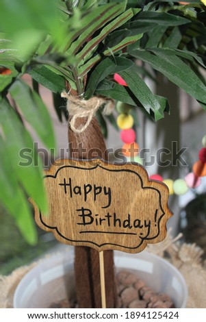 Wooden natural topper happy birthday! on the background of palm trees