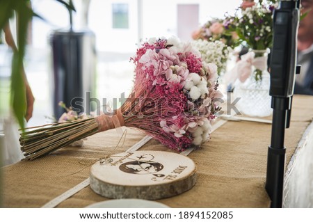 A beautiful wedding ring bearer in the shape of an engraved wood slice, a soft pink flower composition in the background Royalty-Free Stock Photo #1894152085