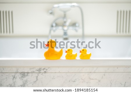 A selective focus shot of cute yellow rubber bath ducks in a row in a bathroom