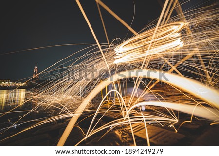 Steel wool photography involves setting light to steel wool and then spinning it in the air to create sparks that light up the dark night sky, creating patterns of light during a long exposure.