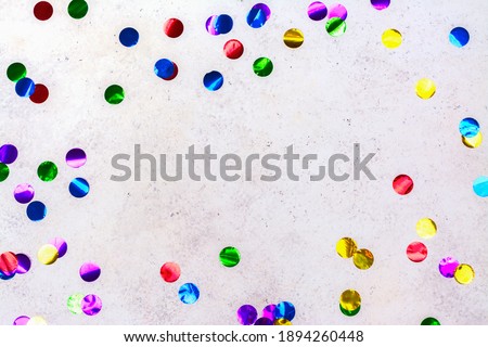 Colorful glitter confetti on light stone background. Carnival concept. Copy space