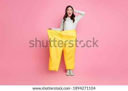 Full body photo of attractive impressed lady hand on head open mouth stand in one pant isolated on pink color background