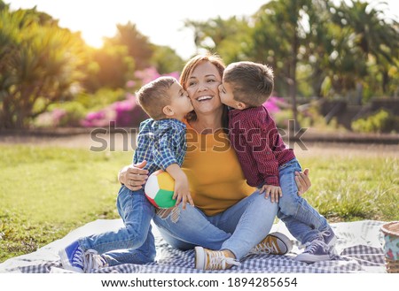 Happy family enjoy day in nature park with a pic nic - Twin brother kissing mother outdoor - Mother and children love 