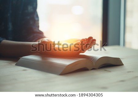 praying hands, young woman prayer  with hands together over a Holy Bible, spiritual light, mind and soul peace Royalty-Free Stock Photo #1894304305