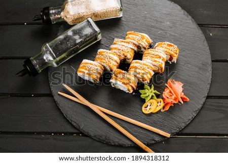 Delicious fresh sushi rolls with seafood and cream cheese on black background
