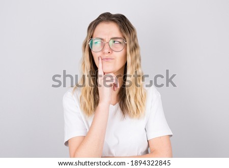 Portrait of young woman thinking with her finger to her head and looks to the side