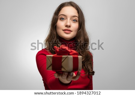 Girl in red with a gift out of focus, joy on her face