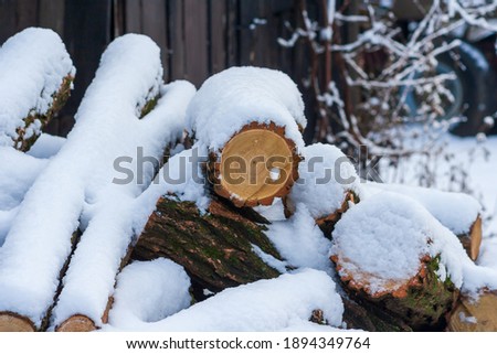 Stack of firewood covered with snow outdoors. Stack of wood cut. Snow on the timber stack. Wooden log store under snow.