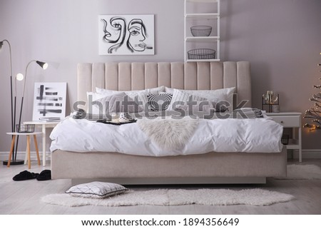 Cozy bedroom interior with cushions and beautiful pictures
