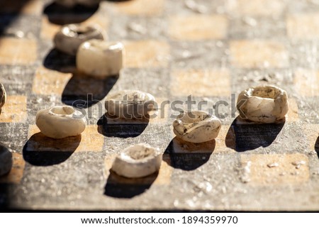 Old rough stone checkers close up. Sunlight, hard shadows.