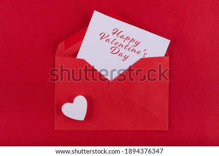 Red envelope containing a white card with a love message and white heart on a red background to congratulate Saint Valetin's day. Concept Valentine's day Royalty-Free Stock Photo #1894376347