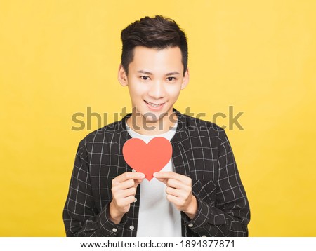 excited young man holding Valentines Day red heart sign 