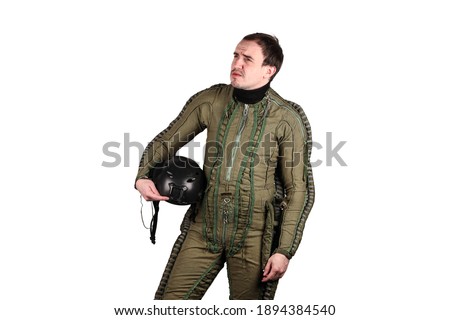 Middle aged pilot in special jumpsuit with helmet in his hand posing in front of camera.