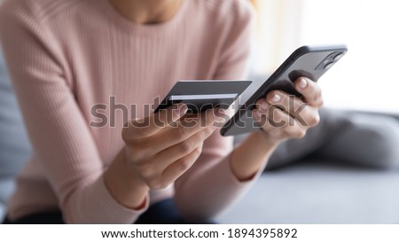 Close up female hands holding credit card and smartphone, young woman paying online, using banking service, entering information, shopping, ordering in internet store, doing secure payment Royalty-Free Stock Photo #1894395892