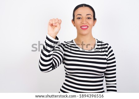 Young beautiful woman wearing stripped t-shirt against white background pointing up with fingers number ten in Chinese sign language Shi