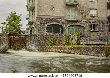 Middle River with the sluice at Fisherman’s Wharf in the east side of the River Corrib, Waterways of Galway, overcast day in Galway City, Connacht Province, Ireland. Long exposure photography