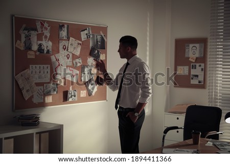 Detective looking at evidence board in office
