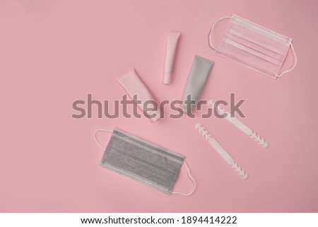 Pink and grey cosmetic tubes and masks on pink paper background. . High quality photo