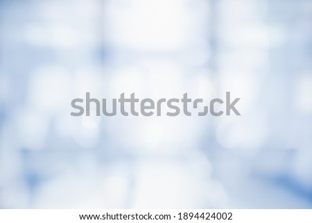 BLURRED OFFICE BACKGROUND, LIGHT BLUE BUSINESS HALL WITH BIG WINDOW AND LIGHT REFLECTIONS