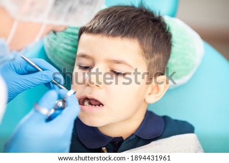 Woman dentist examines child's teeth using metal instruments Royalty-Free Stock Photo #1894431961