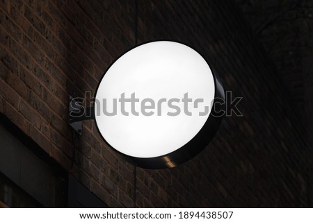 Blank circle sign mockup in the urban environment, on the facade, empty space to display your store sign or logo