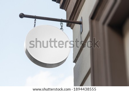 Blank circle sign mockup in the urban environment, on the facade, empty space to display your store sign or logo