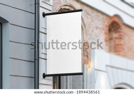 Blank flag sign mockup in the urban environment, on the facade, empty space to display your store sign or logo