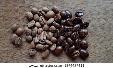 close up shot of arabica beans and robusta beans compared side by side on a wooden background Royalty-Free Stock Photo #1894439611