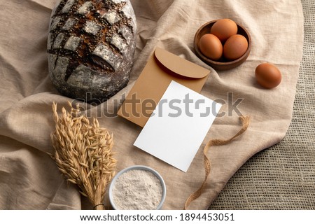 Blank envelope and card on a fabric background with bread, bakery branding mockup, empty space to display your logo or design.