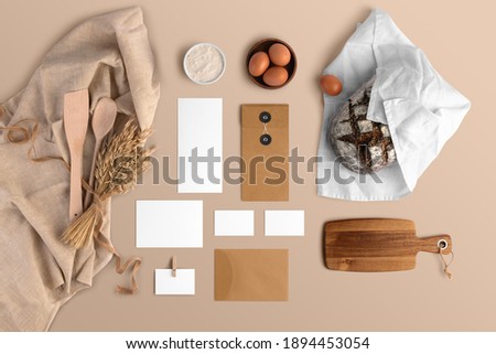 A blank branding set, featuring business cards, envelopes, cards, bread, eggs, flour, serving board, bakery branding mockup, empty space to display your logo or design.