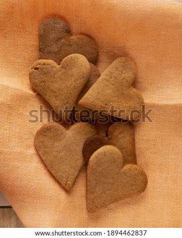Heart-shaped brown homemade gingerbread cookies arranged on an orange napkin.