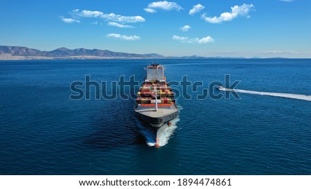 Aerial drone photo of industrial colourful vessel carrying heavy truck size containers cruising the Aegean deep blue sea