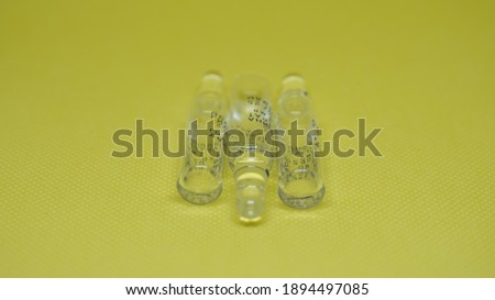 Three transparent glass ampoules on a yellow background. Medical or cosmetic supplement, medical, vaccine, therapy in transparent glass sealed ampoules. translation from Russian: platyphylline hydrota