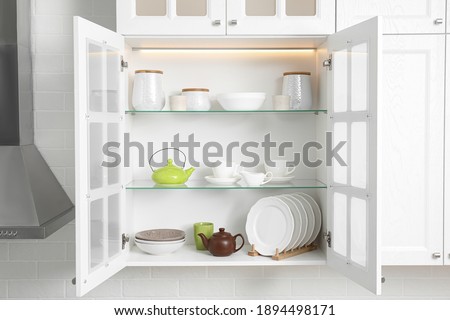 Open cabinet with different clean dishware in kitchen Royalty-Free Stock Photo #1894498171