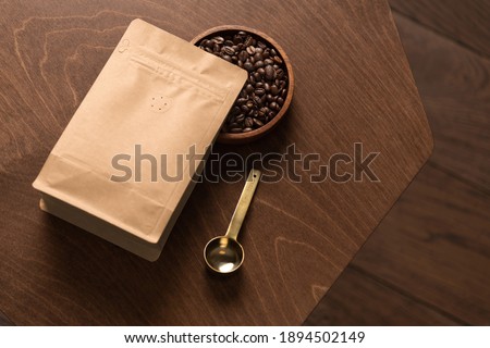 Blank coffee packaging on a wooden table, with coffee seeds bowl, copper spoon, on a wooden background, coffee packaging mockup with empty space to display your branding design.