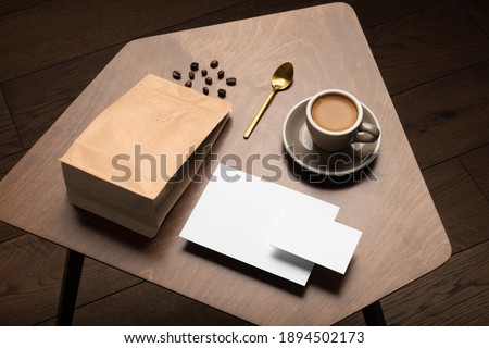 Blank coffee packaging on a wooden table, with empty cards, copper spoon, cup with coffee on a wooden background, coffee packaging mockup with empty space to display your branding design.
