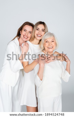 three generation of smiling women looking at camera and hugging isolated on grey Royalty-Free Stock Photo #1894524748