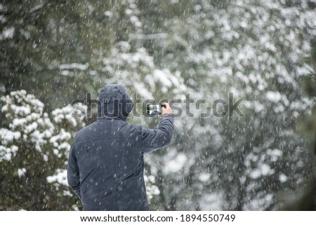 Young boy takes a self-photo with his smart phone in beautiful snowy landscape.Copy space