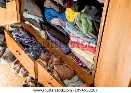 Old clothes and shoes in an overflowing closet. Second hand reuse. Decluttering and cleaning the cabinet. Second hand reuse. Decluttering and cleaning the cabinet Royalty-Free Stock Photo #1894558207
