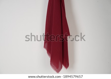 red scarf hung on the wall. Thin fabric texture is commonly used for fashion materials. Fabric mockup for a design template. Muslim veil is empty. Cloth that is attached to the nail on wall.
