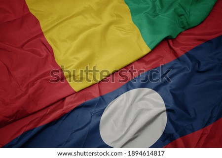 waving colorful flag of laos and national flag of guinea. macro