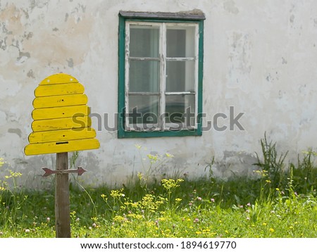 signboard for bee keeping in a meadow with an old house facade in the background